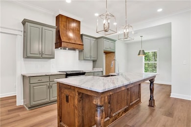 Kitchen featuring light stone counters, decorative backsplash, light wood-style floors, a kitchen island with sink, and recessed lighting