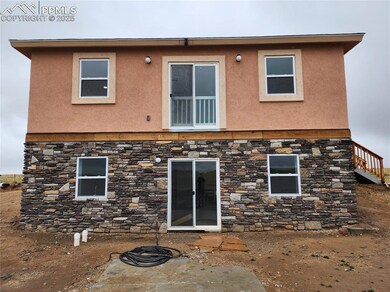 Back of property with stone siding, stucco siding, and a patio area