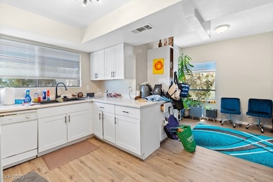 Kitchen with white dishwasher, light wood-style fl