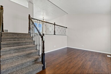 Stairway featuring vaulted ceiling, wood finished floors, a chandelier, and a textured ceiling