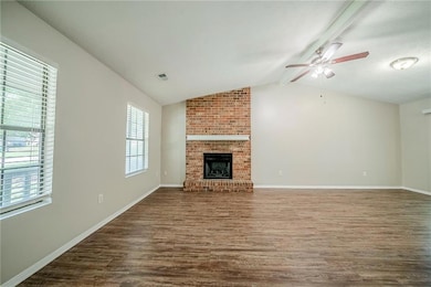 Unfurnished living room with dark wood-style floors, ceiling fan, baseboards, and a fireplace