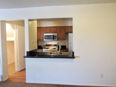 Kitchen with white appliances, a sink, dark counte