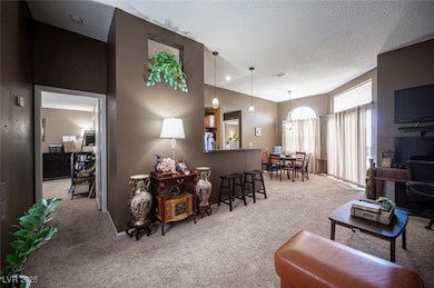 Living room with light carpet, a textured ceiling, a textured wall, and a chandelier