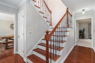 Stairs with crown molding and wood finished floors