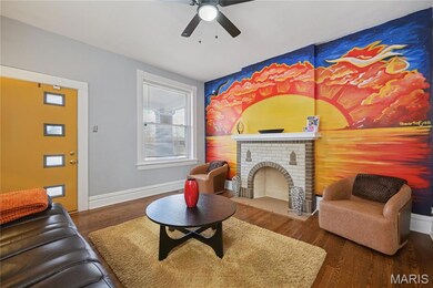 Living room featuring wood finished floors, a fireplace, an accent wall, and a ceiling fan