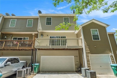 Rear view of house with a garage, central AC unit, driveway, and a balcony