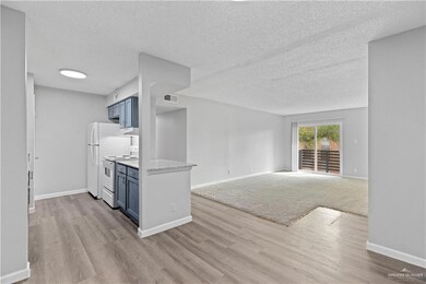 Empty room with a textured ceiling, baseboards, and wood finished floors