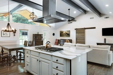 Kitchen with stainless steel gas cooktop, extractor fan, dark hardwood / wood-style flooring, and a barn door