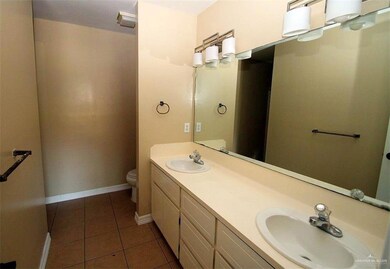 Bathroom with toilet, a sink, tile patterned flooring, and baseboards