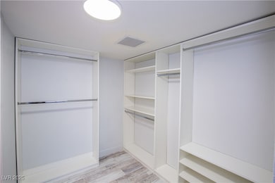 Walk in closet with light wood finished floors and
