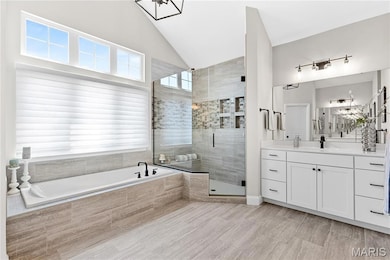Bathroom with a bath, vanity, a stall shower, and lofted ceiling