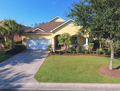 View of front of property featuring stucco siding, a front lawn, a garage, and driveway
