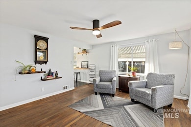 Living area featuring dark wood-style flooring and a ceiling fan
