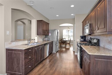 Kitchen with a sink, light stone counters, dark wo