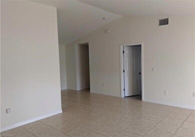 Empty room with vaulted ceiling and light tile patterned floors