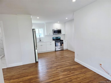 Kitchen featuring white cabinetry, stainless steel appliances, dark wood finished floors, and recessed lighting