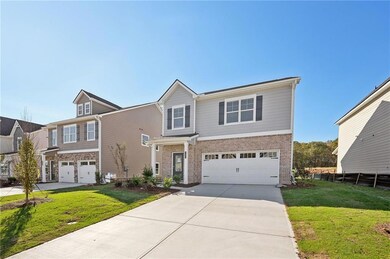 View of front of property featuring a garage, driveway, brick siding, and a front lawn