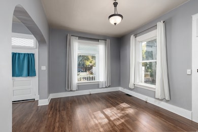 Dining area with dark wood-type flooring and arched walkways