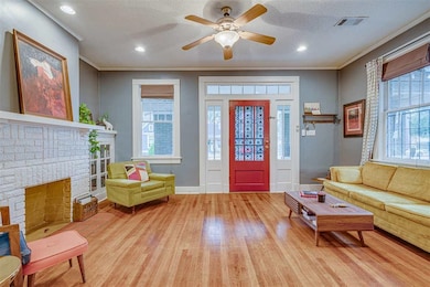 Entrance foyer with wood finished floors, crown molding, a ceiling fan, baseboards, and a brick fireplace
