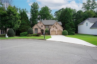 View of front of home with driveway, a chimney, brick siding, and a front yard