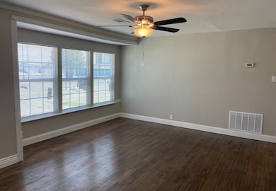 Unfurnished room with visible vents, dark wood finished floors, and baseboards