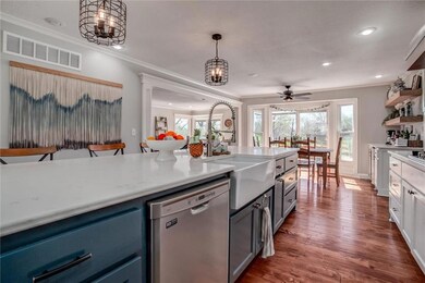 Kitchen featuring hanging light fixtures, dark hardwood / wood-style floors, ceiling fan with notable chandelier, white cabinets, and dishwasher