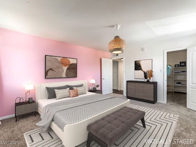 Carpeted bedroom with a walk in closet, a skylight