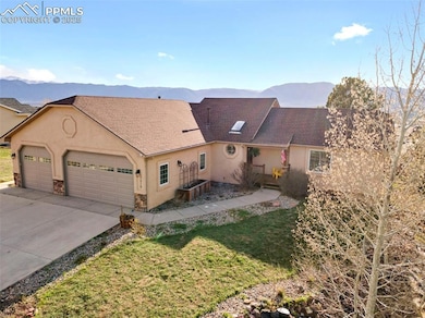 View of front of property featuring a mountain view, stone siding, an attached garage, and stucco siding