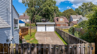 Fenced backyard featuring an outbuilding, a garage, and a residential view