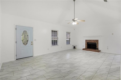 Unfurnished living room with ceiling fan, a fireplace, light marble finish flooring, and a towering ceiling