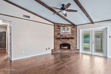 Unfurnished living room featuring a brick fireplace, wood finished floors, ceiling fan, and wood walls