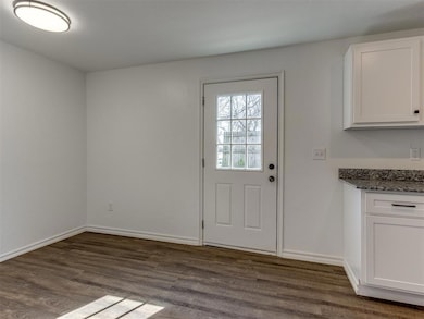 Doorway to outside with dark wood-style flooring and baseboards