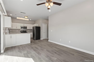 Kitchen with appliances with stainless steel finishes, white cabinets, recessed lighting, light wood-type flooring, and open floor plan