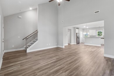 Unfurnished living room with high vaulted ceiling, ceiling fan with notable chandelier, and wood-type flooring