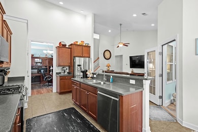 Kitchen with an office area, high vaulted ceiling, light tile patterned flooring, appliances with stainless steel finishes, and brown cabinets