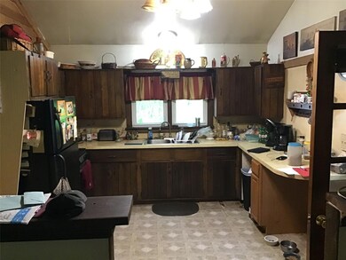 Kitchen featuring freestanding refrigerator, a sink, light countertops, vaulted ceiling, and light floors