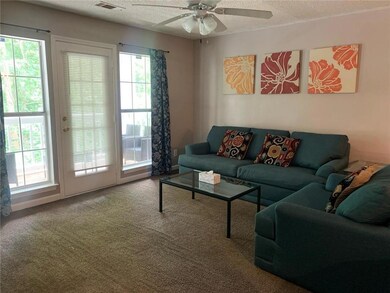 Carpeted living room featuring plenty of natural light, a textured ceiling, and ceiling fan