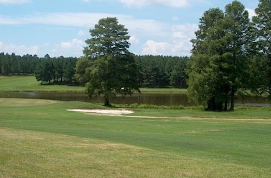 View of community featuring a yard, a forest view, a water view, and view of golf course