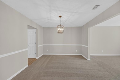 Carpeted empty room with an inviting chandelier, b