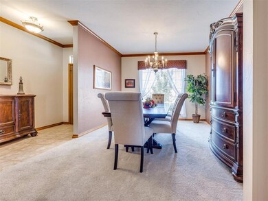 Dining area with a chandelier, light colored carpet, and ornamental molding