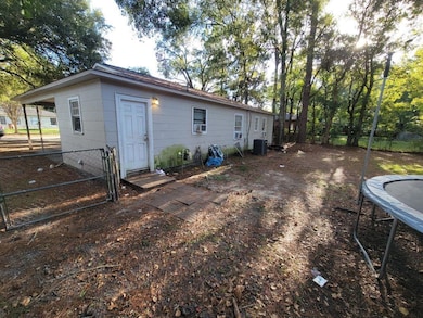 Back of house featuring a gate, a trampoline, and crawl space