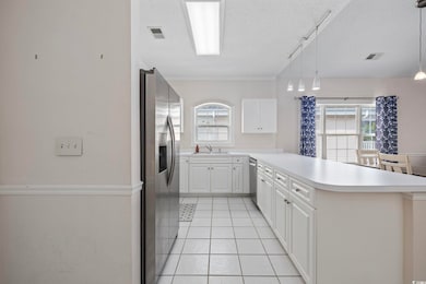 Kitchen featuring stainless steel appliances, a textured ceiling, a peninsula, light countertops, and a sink