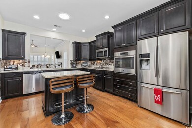 Kitchen with light hardwood / wood-style flooring, stainless steel appliances, decorative backsplash, a breakfast bar area, and ceiling fan