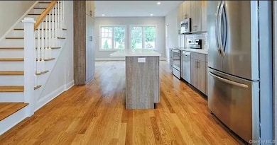 Kitchen featuring a kitchen island, stainless steel appliances, light wood-type flooring, backsplash, and recessed lighting