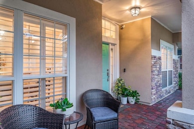 Property entrance featuring stucco siding, stone siding, and a patio area