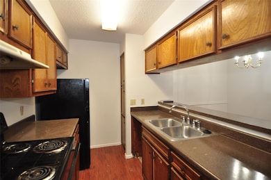 Kitchen featuring black / electric stove, dark wood finished floors, dark countertops, a textured ceiling, and a chandelier