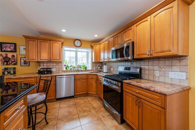 Kitchen with appliances with stainless steel finishes, light stone counters, decorative backsplash, light tile patterned floors, and brown cabinetry