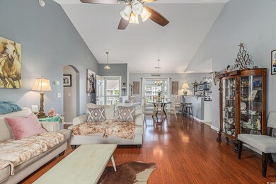 Living area featuring arched walkways, a ceiling fan, wood finished floors, high vaulted ceiling, and baseboards