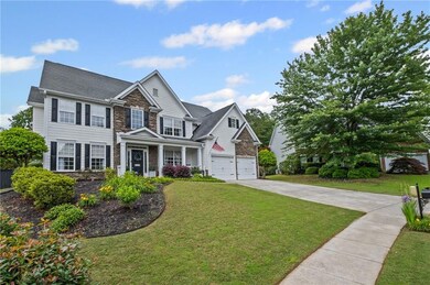 View of front of home with stone siding, driveway, a front lawn, and an attached garage