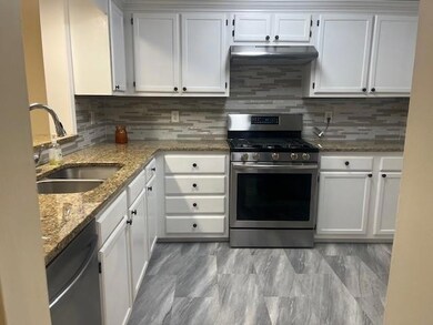 Kitchen with appliances with stainless steel finishes, a sink, extractor fan, and white cabinets
